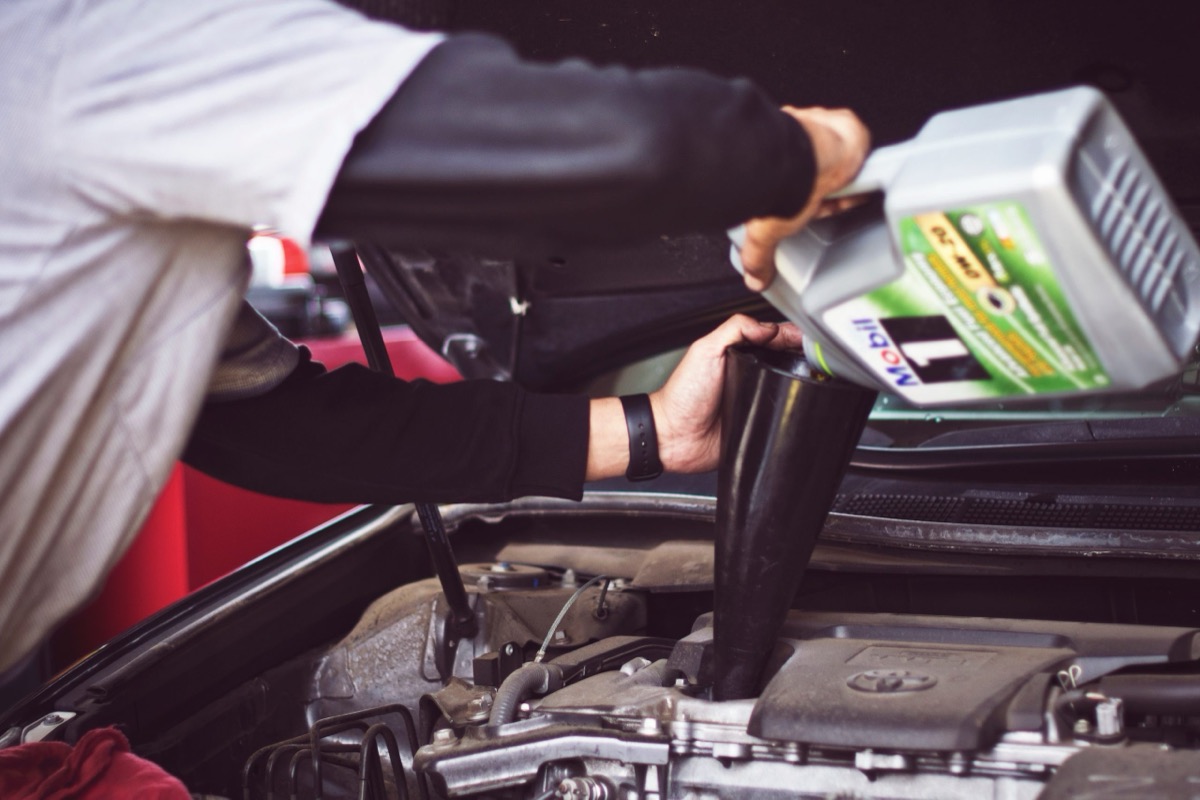 Mechanic pouring fresh oil into a Toyota engine during a service
