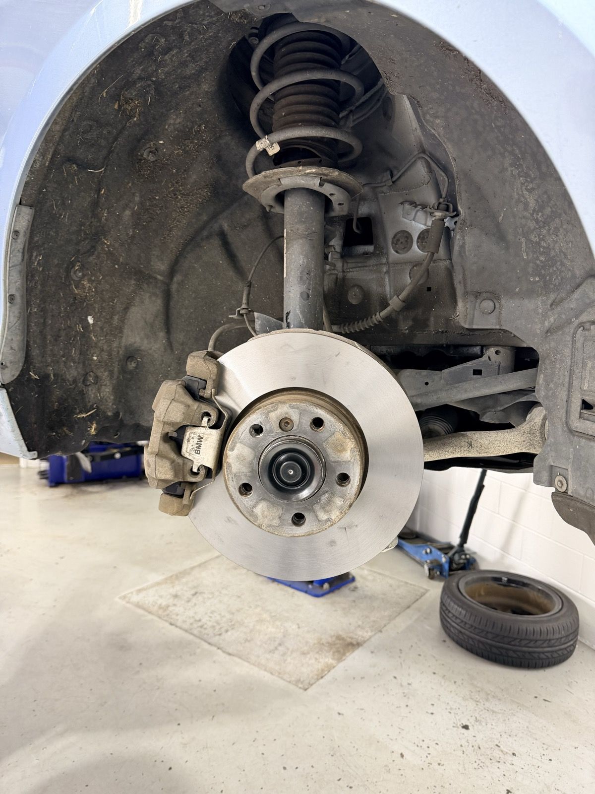 BMW front strut, coil spring and brake rotor exposed during suspension work